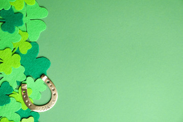Flat lay composition with clover leaves and horseshoe on green background, space for text. St....