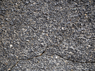 An old cracked wall is covered with pebbled stucco. Pebbles of different sizes and shapes. Gray stone retro background.
