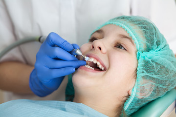 A woman dentist doctor brushes the teeth of a teenage child with a special medical brush. Inspection of the oral cavity of the girl. Modern technologies in dentistry.