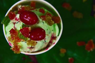 paan flavoured green betel ice cream garnished with cherry and tooty fruity on betel leaves