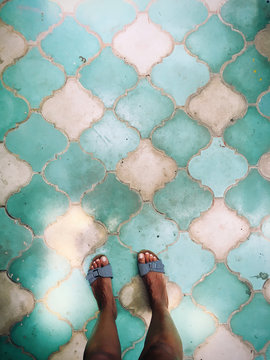 Overhead view of woman's feet in sandals on blue and white tiled floors