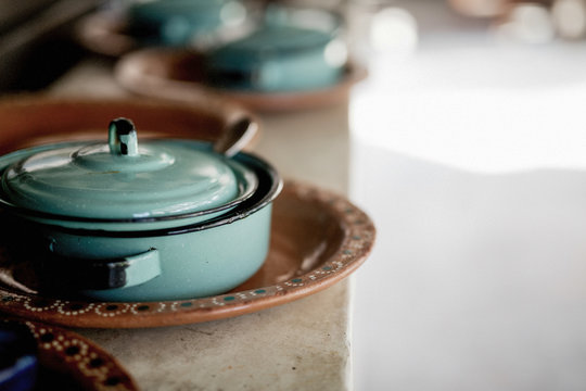 Turquoise enamel covered pot on painted terracotta plate