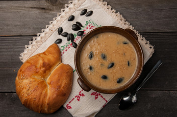 Traditional Ecuadorian food sweet sambo on a brown ceramic plate with a bread on one side and sambo seeds on a white tablecloth on a rustic wooden table