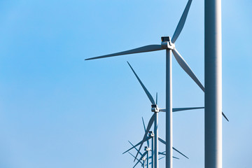 Farm of wind turbines bright blue sky on background