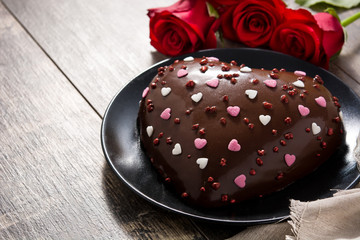 Heart shaped cake and red roses on wooden table