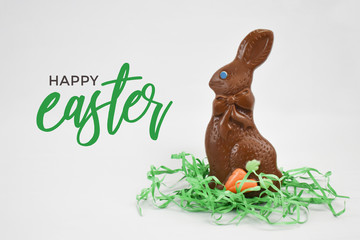 Happy Easter Greeting Card Text With Chocolate Easter Bunny Candy and Green Grass Isolated Over White Background