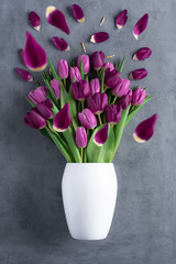 bouquet of tulips in white vase on stone grey background