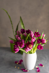 bouquet of tulips in white vase on stone grey background