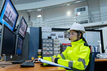 Inside the large Industry Factory Female Computer Engineer Works on Personal Computer She coding program for control machine,Thailand people work on fours monitors,Programmer working with serious