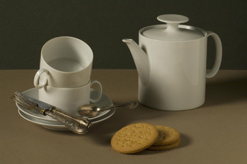 Tè e biscotti su fondo verde, still life con tazze teiera, biscotti e cucchiaini