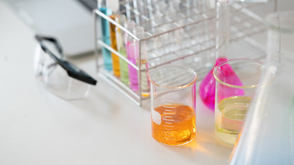 Photo of laboratory glassware containing colored liquids and safety glasses while putting together...