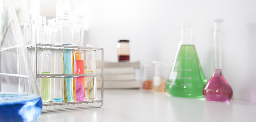 Photo of laboratory glassware containing colored liquids while putting together on white table isolated over white background.