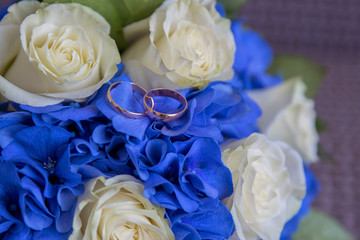 wedding rings on a bouquet of blue and white flowers