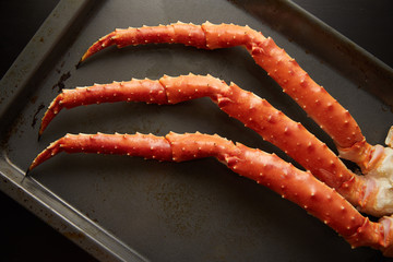 Closeup image of fresh crab phalanges on oven-tray over dark background with copyspace © strixcode