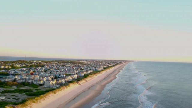 Aerial flight down coastline with view of community at sunrise. Corolla, NC. Outer Banks.