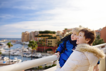 Fototapeta na wymiar Grandmother and her little grandchild looking on yachts and boats in port of Monaco in winter day.