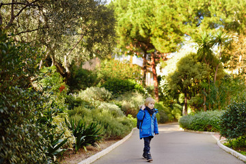 Little boy walking in park of Monaco in sunny winter day.