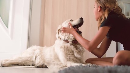 Young teenager girl playing happily with pet dog on the floor