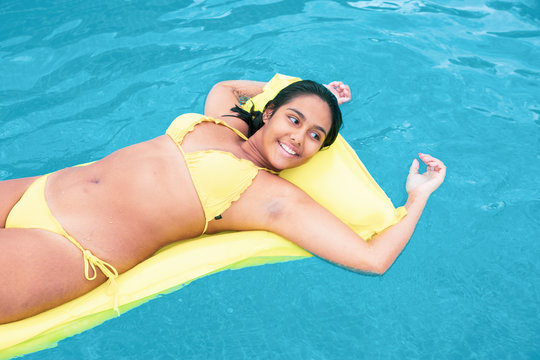 Curvy young Woman floating on inflatable tube in summer in swimming pool 