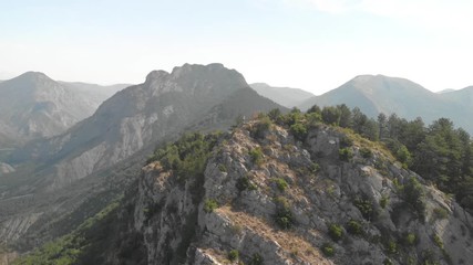 Aerial orbit lanscape view around man standing on top of green rocky mountain