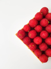 French dessert. Tart with raspberries. Almond frangipane and raspberry coulis inside of a tart. Decorated with fresh raspberries and lime zest. White background. Top view.