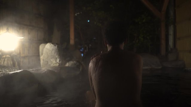 Back View of A Young Female In Outdoor Hot Spring Bath in Japan During Nighttime- Close Up Shot