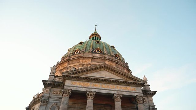 Ancient European Architecture rise up view. Frederick`s church and Kierkegaard statue during golden hour sunset. Inscription under dome The Lord's word remains forever. Sunny winter day in Copenhagen.