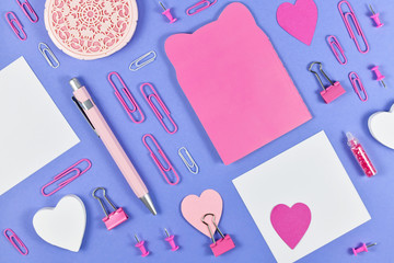 Flat lay with various pink arranged office supplies like pen, note book, blank note paper, pins or...