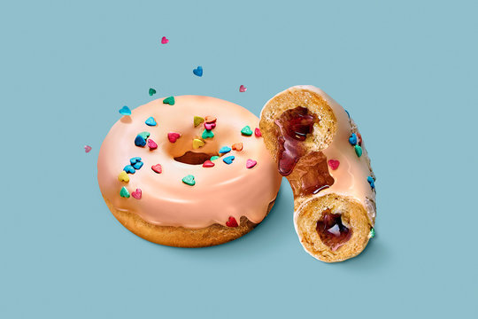 Appetizing donut with pink icing, flying topping and caramel filling on isolated on colored (blue) background. Cut donut. Classic American dessert pastry. Packshot