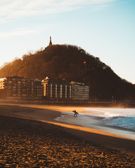 Surfer walking away from the shore on Zurriola Beach, San Sebastian