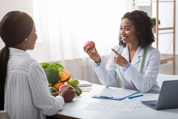 Nutritionist giving consultation to patient with healthy fruit and vegetable - obrazy, fototapety, plakaty