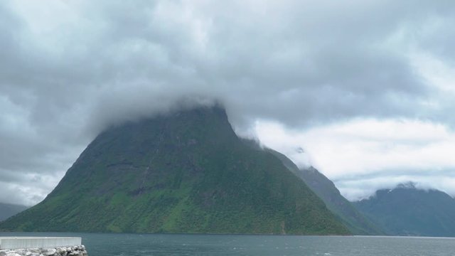 clouds slowly passing the mountain peak in a norwegian fjord - dramatic scenery