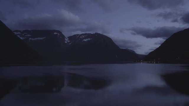 Panning shot of a norwegian fjord at night - Distant lights from the village of Urke