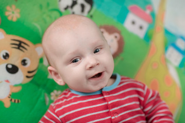 Cute little baby boy lying on his back smiling