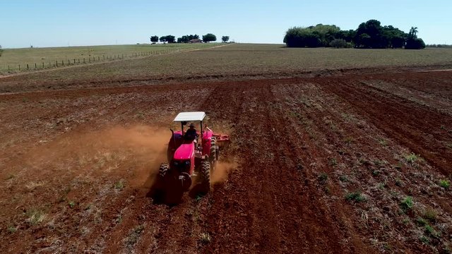 Aerial drone following a tractor preparing the soild for seed planting