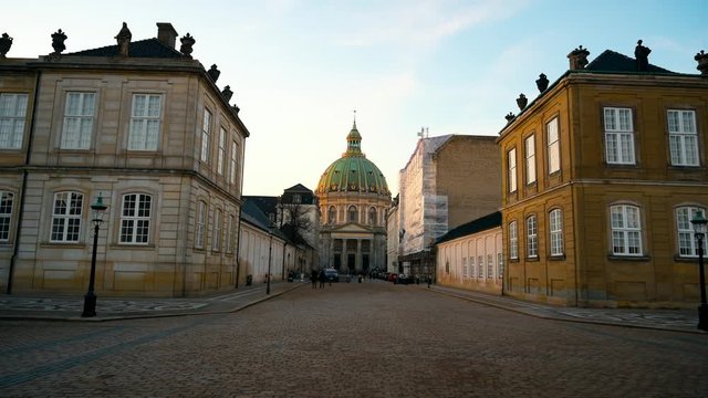 Ancient European Architecture follow view. Frederick`s church and Kierkegaard statue during golden hour sunset. Moving forward from Amalienborg square. Sunny winter day in Copenhagen.