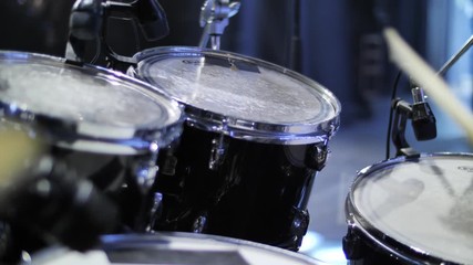 Playing on drum set, drumsticks beating toms close up