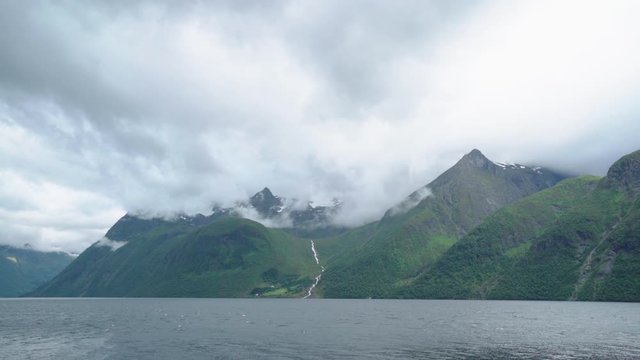 Clouds slowly moving in different directions around mountain top in a Norwegian fjord -