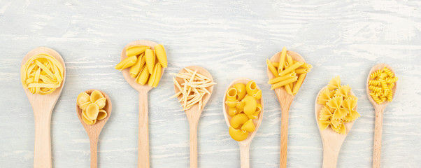 Flat lay with different types of traditional italian pasta. Penne, tagliatelle, fusilli, farfalle,...