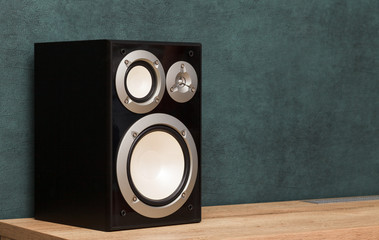 Audio speaker in interior on wooden desk near green wall