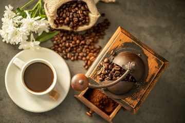 cup of coffee with beans and grinder