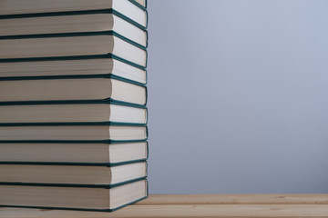 A stack of books with a green cover lying on a wooden table and depicted on a light gray background...
