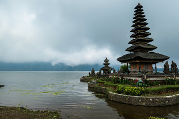 Fototapeta na wymiar A view on the front of main building of Ulun Danu Temple, Bali, Indonesia. Beautiful of Hindu water temple. Sacred place. Discovering new cultures. Cloudy day. The temple is surrounded by water