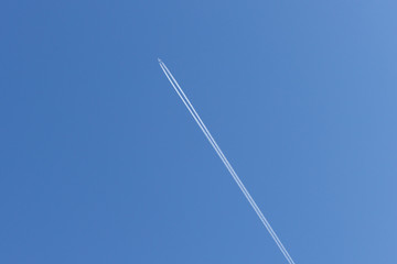 Trail of an airplane piercing the blue sky