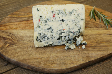 piece of blue cheese captured isolated on a wooden board isolated on a wooden table. Organic farm dairy products