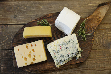 assortment of cheese maasdam and parmesan and blue cheese captured and feta on a wooden board. Organic farm dairy products. Flat lay. Top view