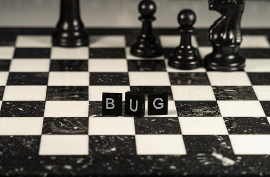 bug concept represented by black and white letter tiles on a marble chessboard with chess pieces