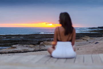 Fototapeta na wymiar Girl sitting on the beach enjoying the sunset