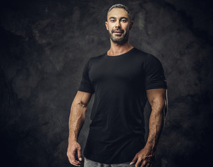 Gorgeous, adult, fit muscular caucasian man coach posing for a photoshoot in a dark studio under...