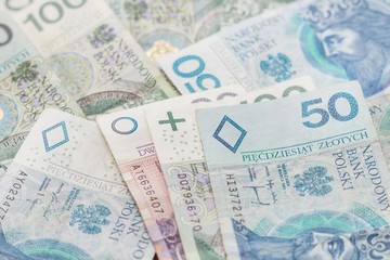 Banknoty PLN o nominałach 20, 50 i 100 zł leżą na stole.